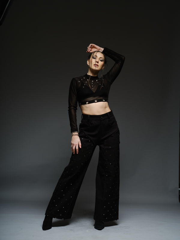 Black high-neck velvet mesh crop top with metallic rivets, paired with wide-leg black denim pants with silver-tone studs