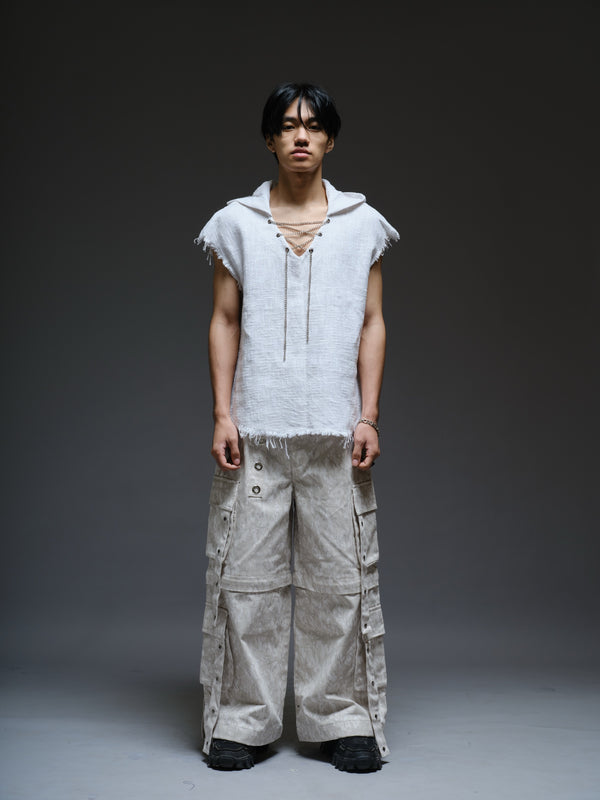 Sleeveless hooded cotton jute top with frayed edges, paired with printed camo denim cargo pants with oversized flap pockets and hanging straps
