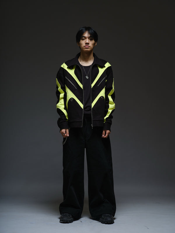 Black denim jacket with neon panels across the chest and sleeves, decorative silver zippers, large metal eyelets and a broad collar.
