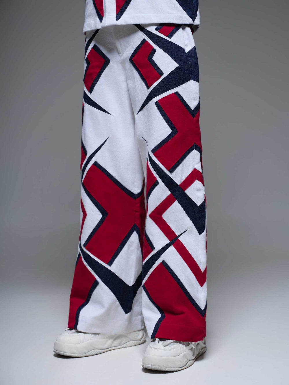 MAZE MATRIX PANTS: Black pants with a white geometric maze print, featuring a relaxed fit and cargo pockets.