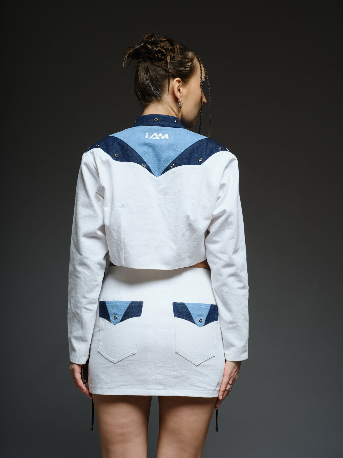 White and blue panelled denim cropped jacket and A-line skirt with metal rivets and criss-cross cord detailing
