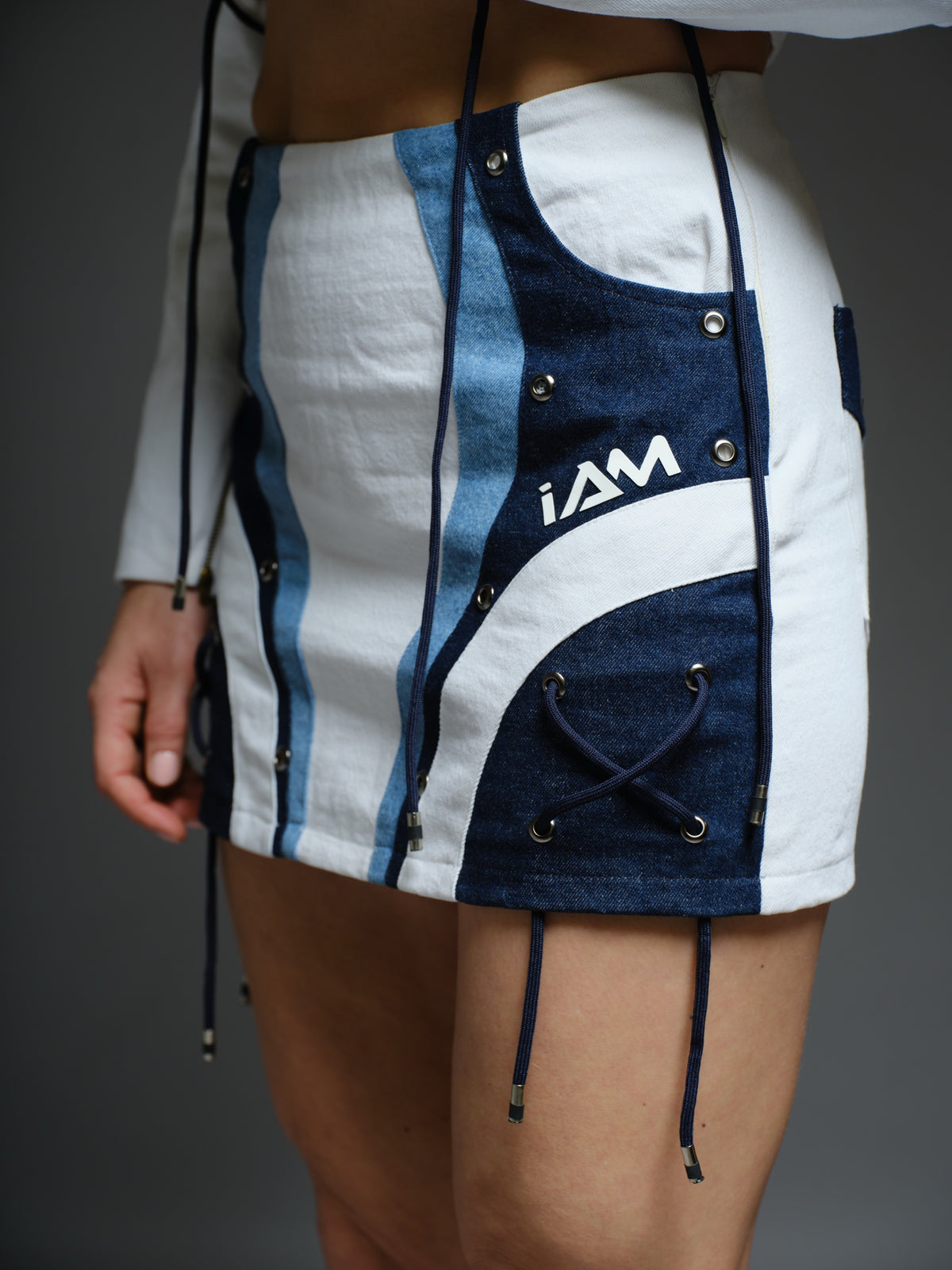 White and blue panelled denim cropped jacket and A-line skirt with metal rivets and criss-cross cord detailing