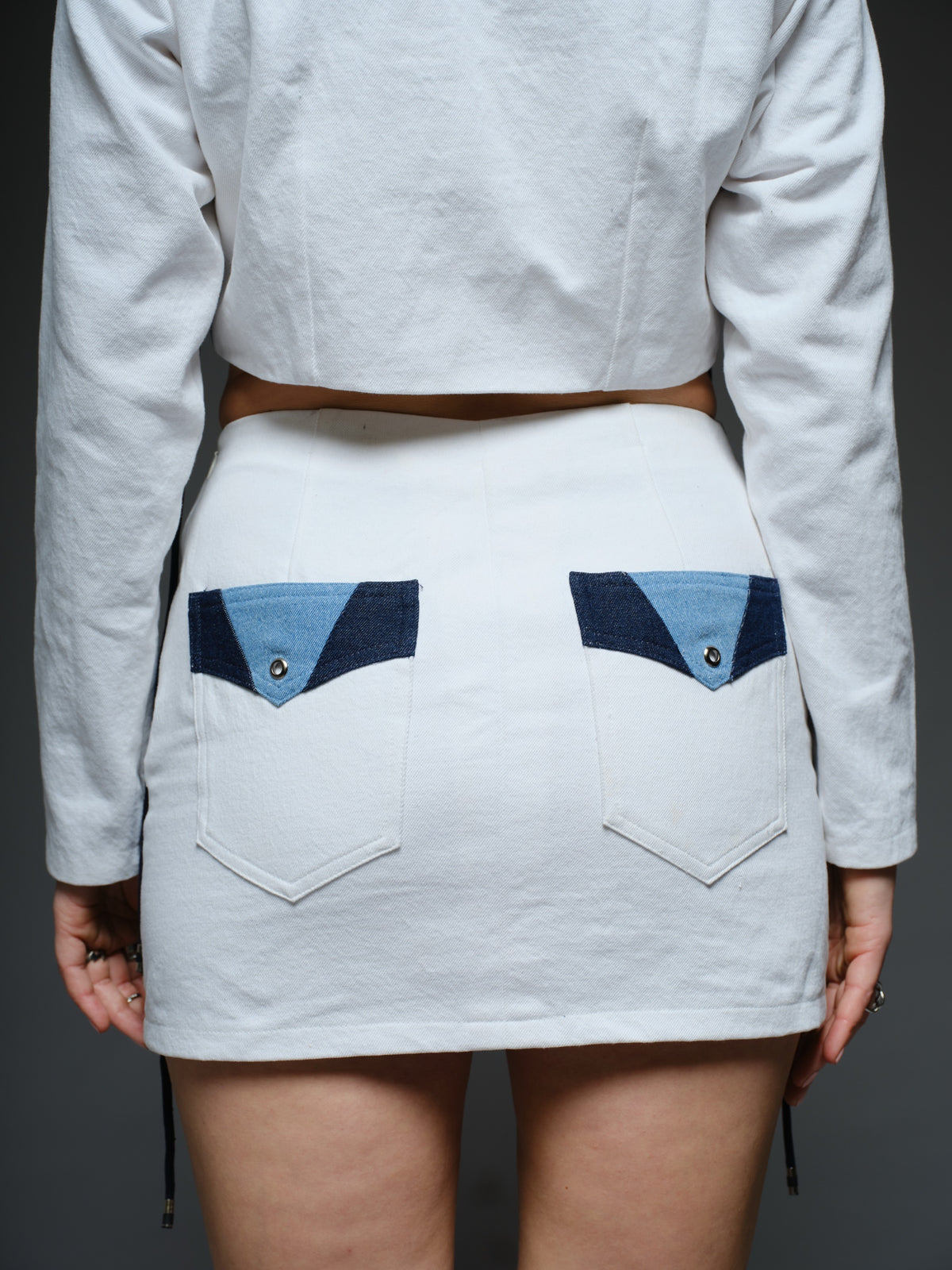 White and blue panelled denim cropped jacket and A-line skirt with metal rivets and criss-cross cord detailing