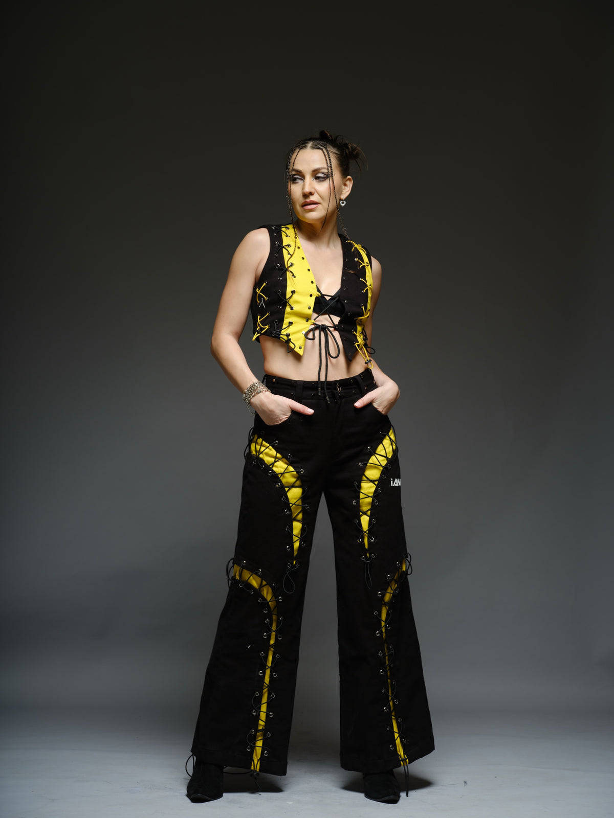 Yellow and black denim cropped vest and baggy trousers with criss-cross lacing, metal hardware and a studded waistband