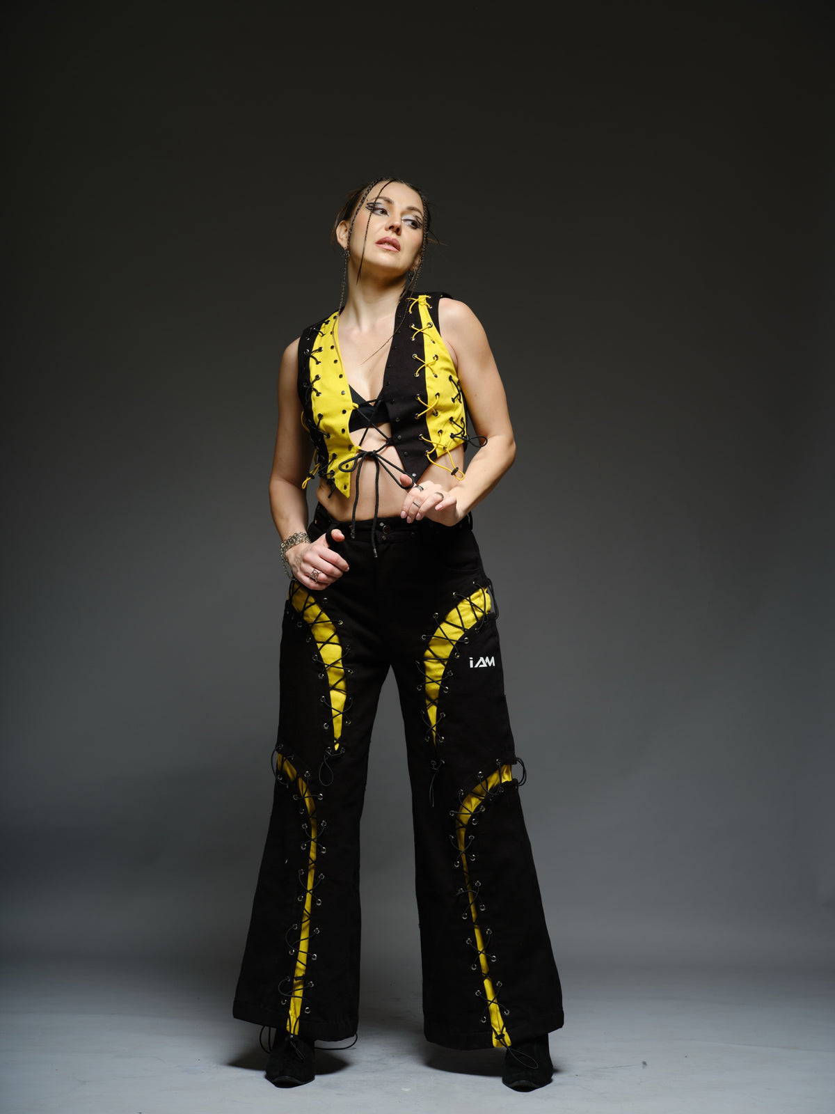 Yellow and black denim cropped vest and baggy trousers with criss-cross lacing, metal hardware and a studded waistband