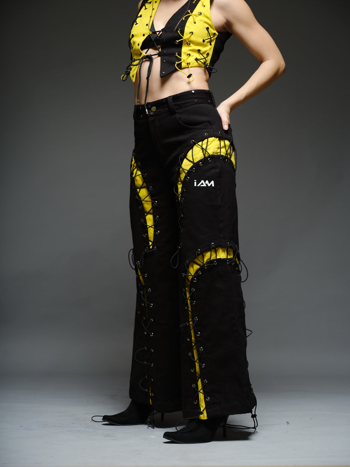 Yellow and black denim cropped vest and baggy trousers with criss-cross lacing, metal hardware and a studded waistband