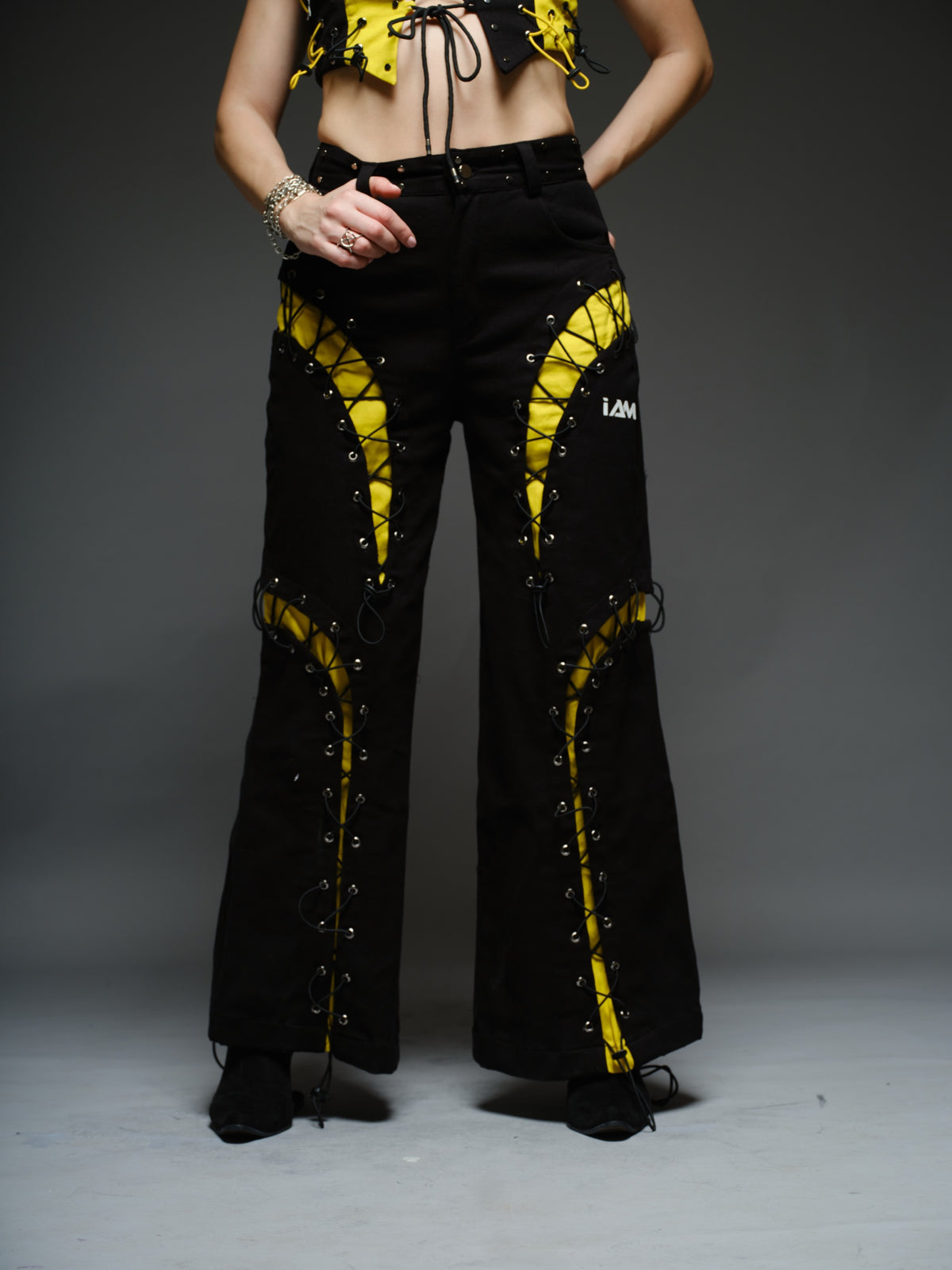 Yellow and black denim cropped vest and baggy trousers with criss-cross lacing, metal hardware and a studded waistband