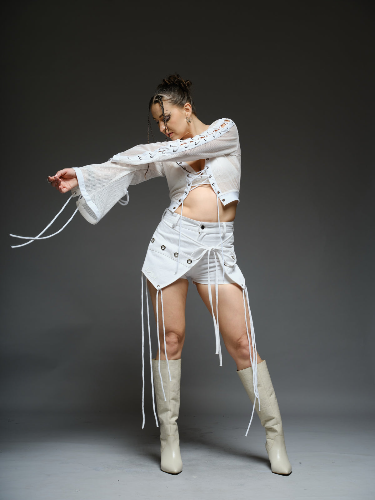 White net cropped top with front and sleeve lacing, paired with a white denim wrap mini skort with cords and metallic details