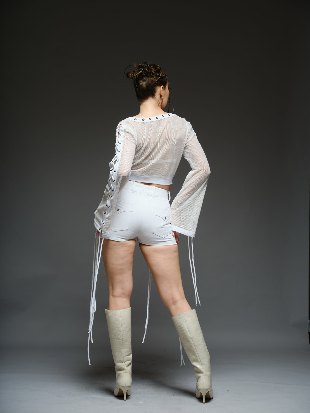 White net cropped top with front and sleeve lacing, paired with a white denim wrap mini skort with cords and metallic details