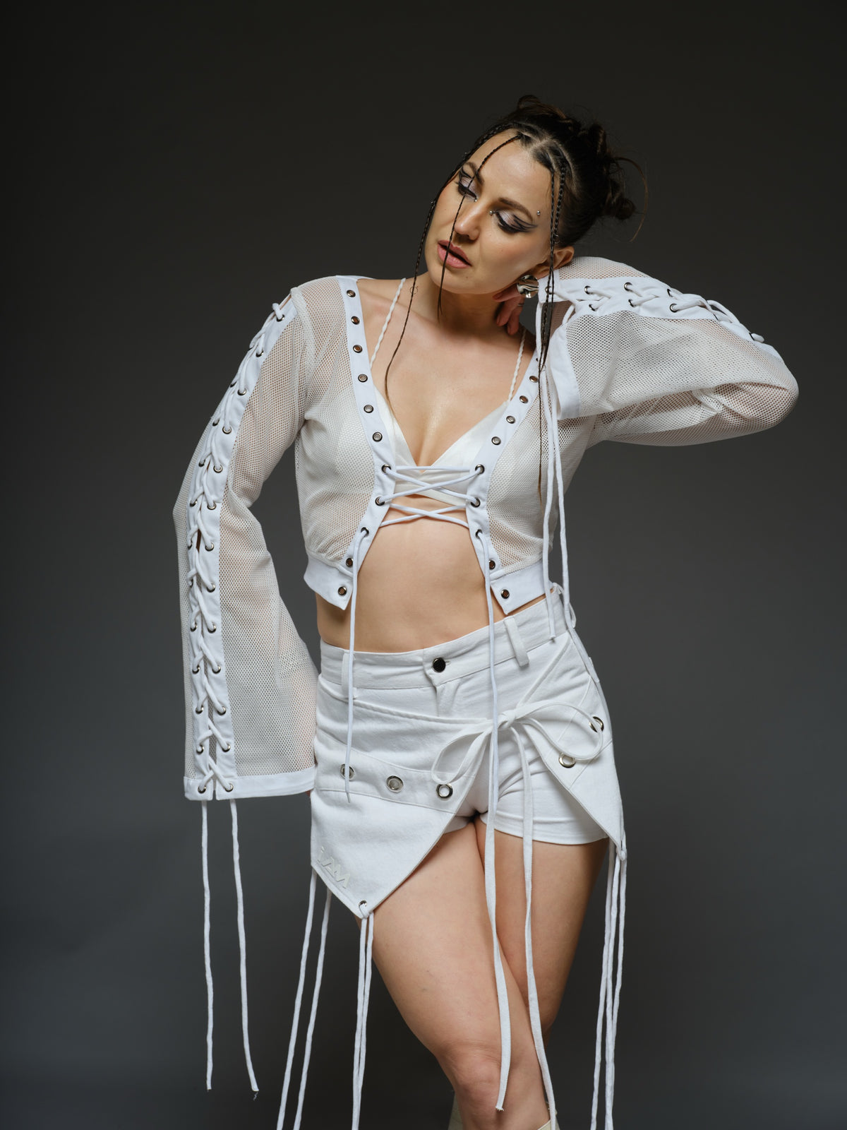 White net cropped top with front and sleeve lacing, paired with a white denim wrap mini skort with cords and metallic details
