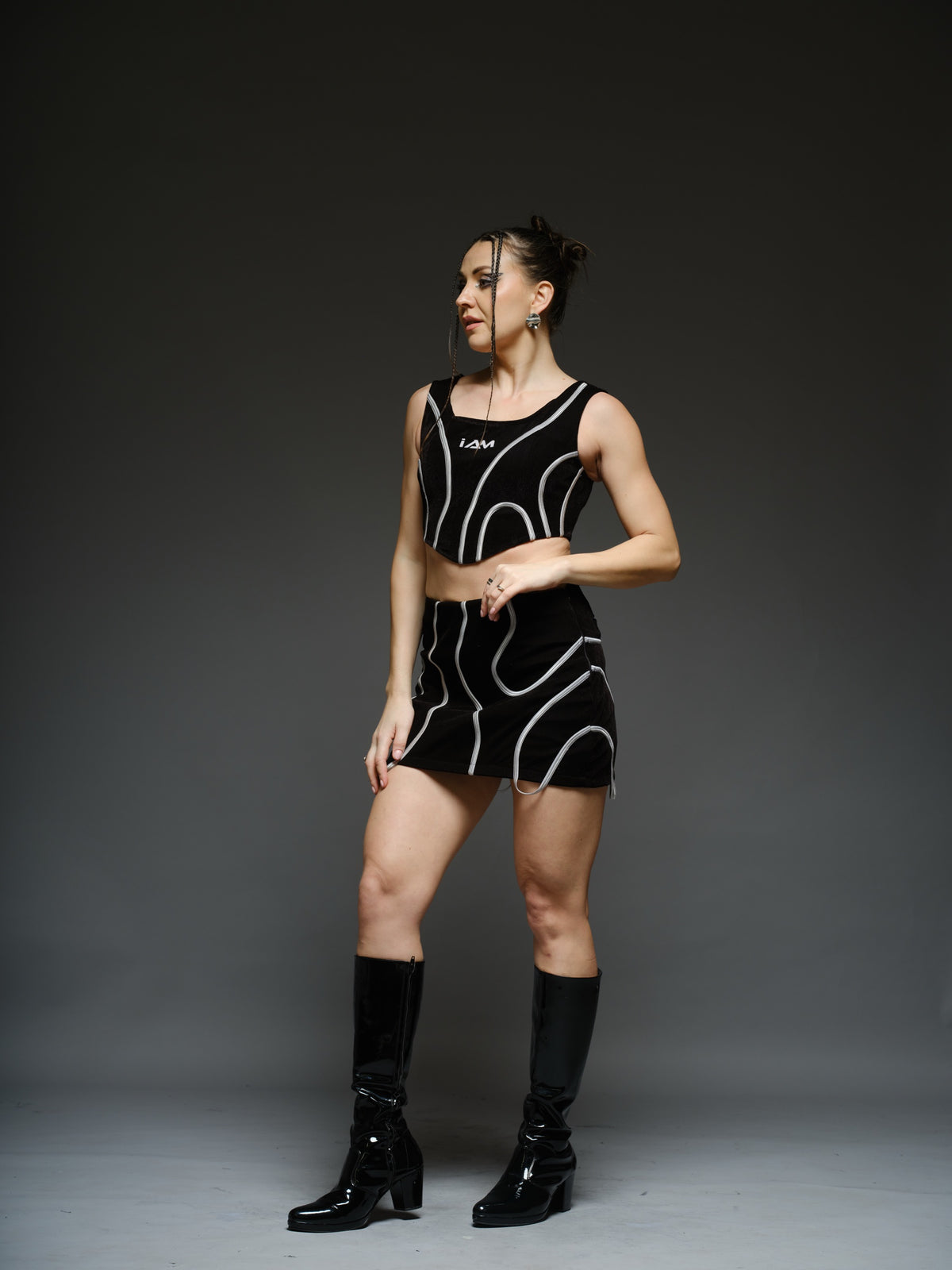 Black crop top and mini skirt with light-coloured curved cord detailing and loops extending below the skirt hem