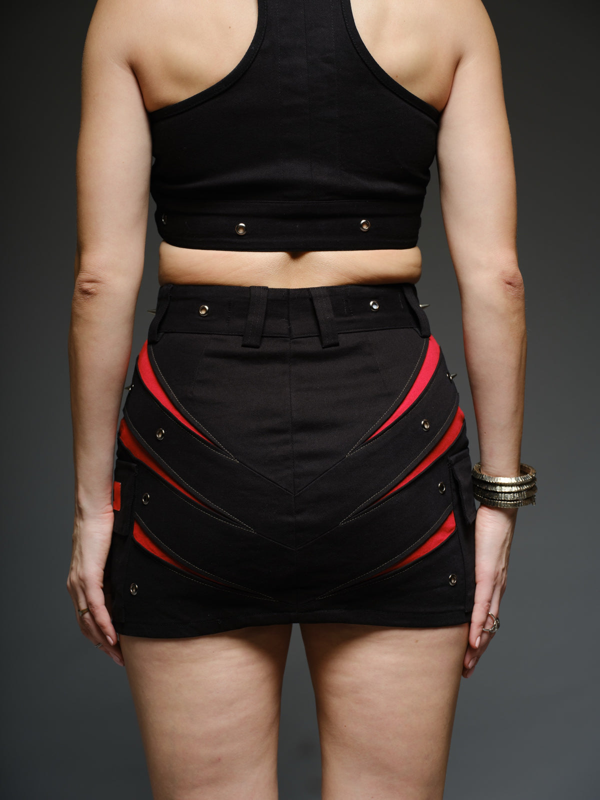 Black denim halter crop top and fitted mini skirt with red claw-shaped inserts, silver-tone rivets and exposed front zippers.
