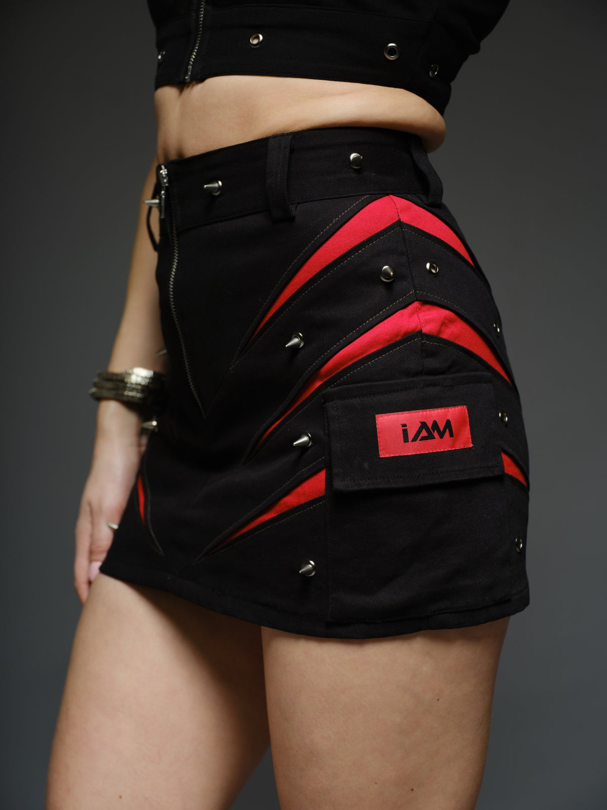 Black denim halter crop top and fitted mini skirt with red claw-shaped inserts, silver-tone rivets and exposed front zippers.