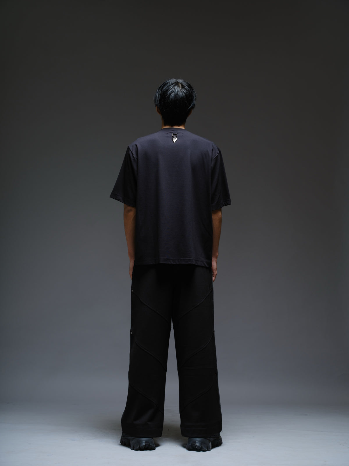 Loose black wide-leg trousers with grey net side panels and small silver-tone studs at the panel corners