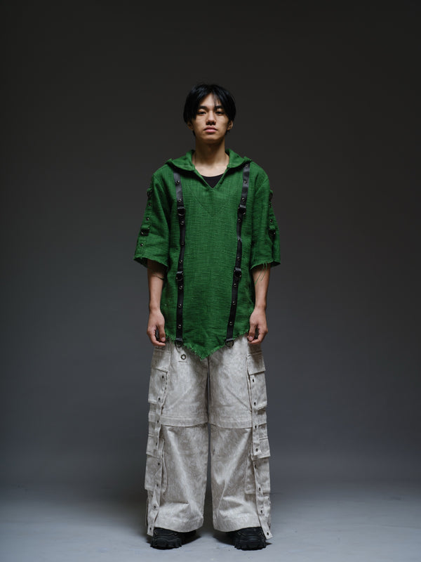 Dark olive hooded poncho with black straps and D-rings, paired with convertible camo denim cargo pants