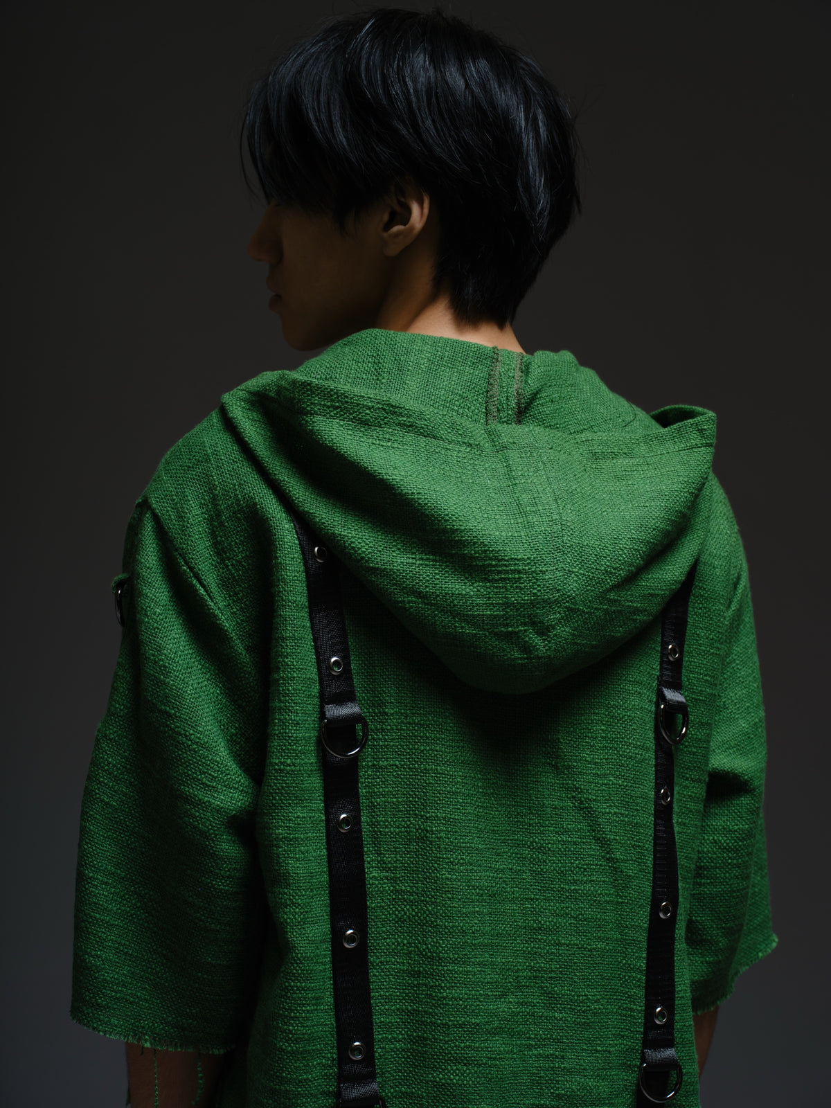 Dark olive hooded poncho with black straps and D-rings, paired with convertible camo denim cargo pants
