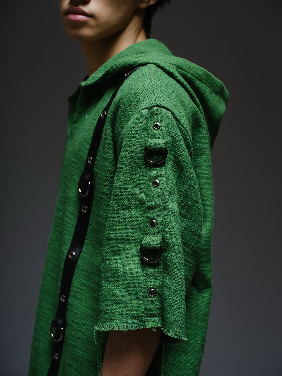 Dark olive hooded poncho with black straps and D-rings, paired with convertible camo denim cargo pants