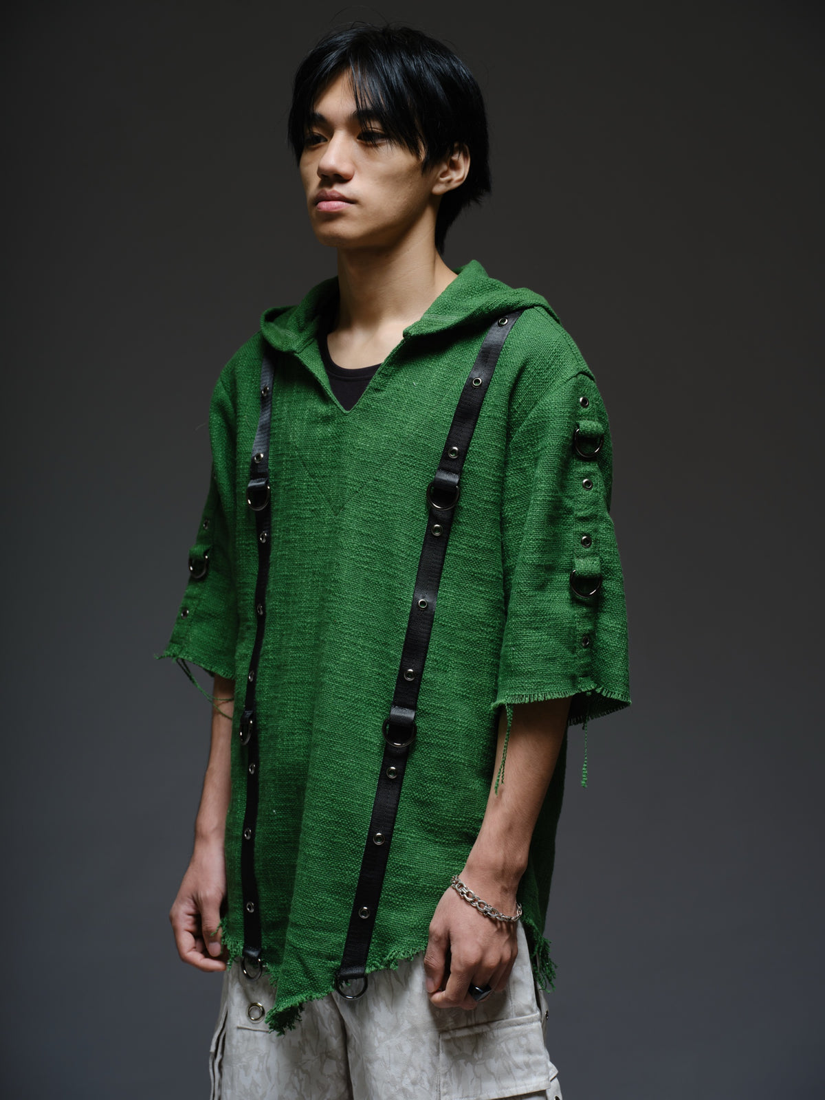 Dark olive hooded poncho with black straps and D-rings, paired with convertible camo denim cargo pants