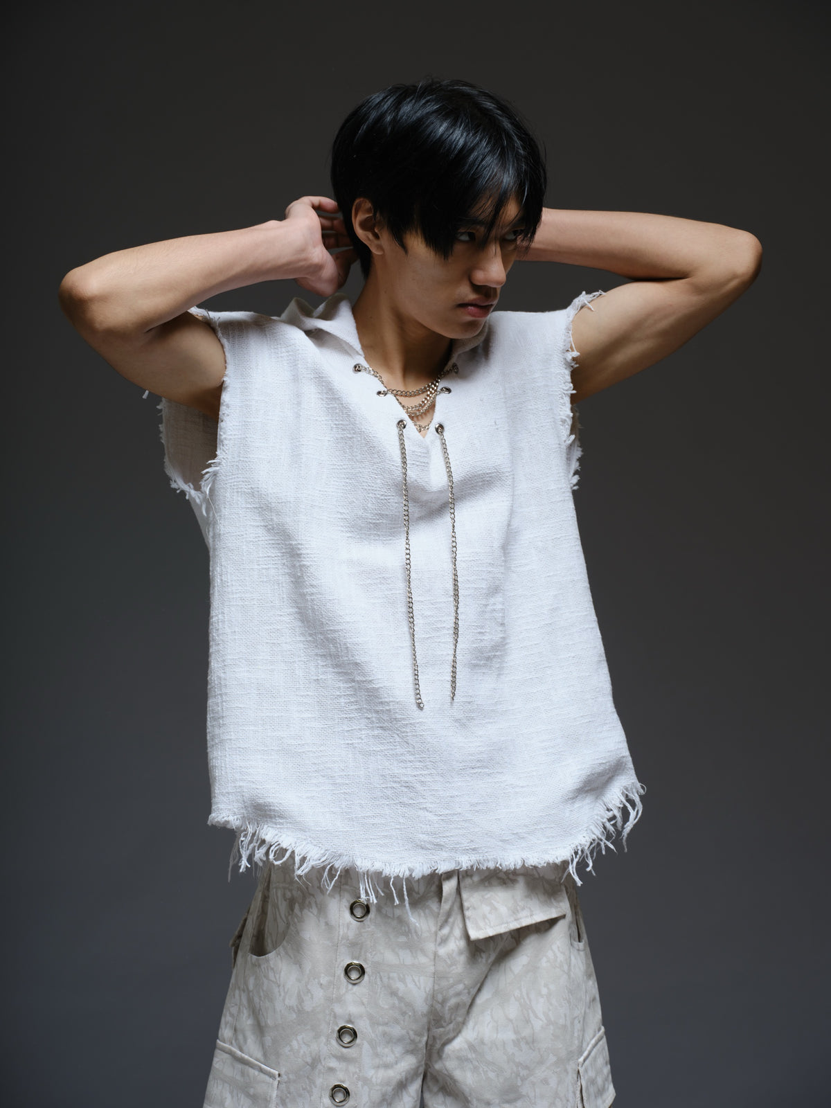 Sleeveless hooded cotton jute top with frayed edges, paired with printed camo denim cargo pants with oversized flap pockets and hanging straps