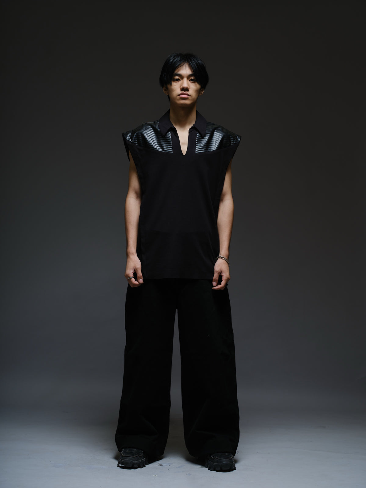 Onyx black sleeveless Roma knit tee with extended shoulders, stitched leather chest panels, a pointed collar and an open V neckline