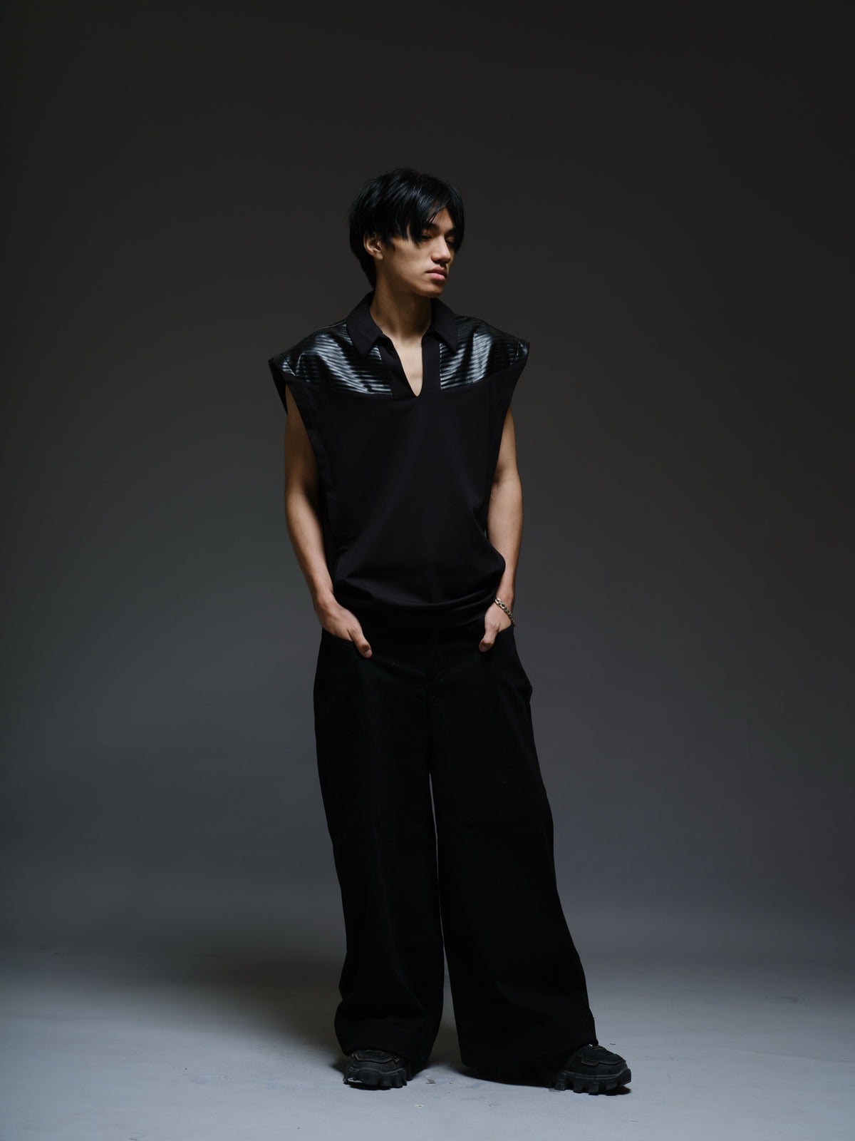 Onyx black sleeveless Roma knit tee with extended shoulders, stitched leather chest panels, a pointed collar and an open V neckline