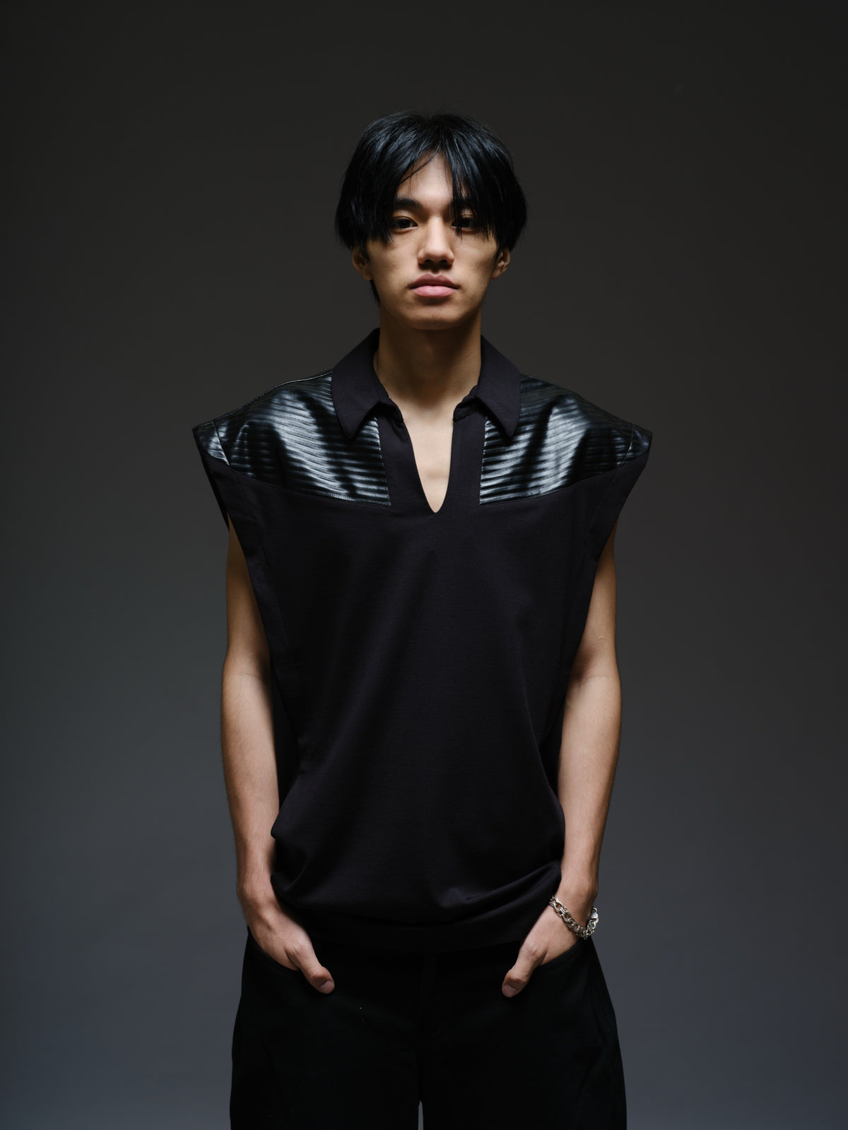 Onyx black sleeveless Roma knit tee with extended shoulders, stitched leather chest panels, a pointed collar and an open V neckline