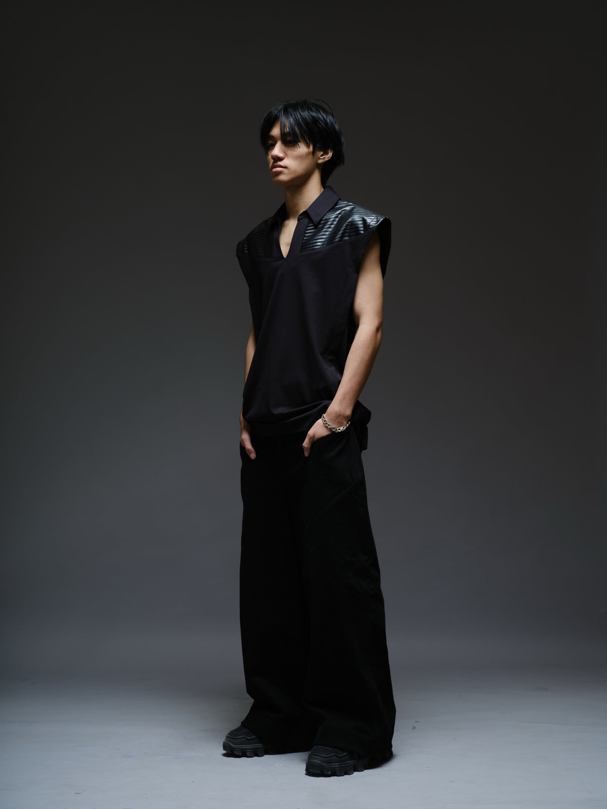 Onyx black sleeveless Roma knit tee with extended shoulders, stitched leather chest panels, a pointed collar and an open V neckline