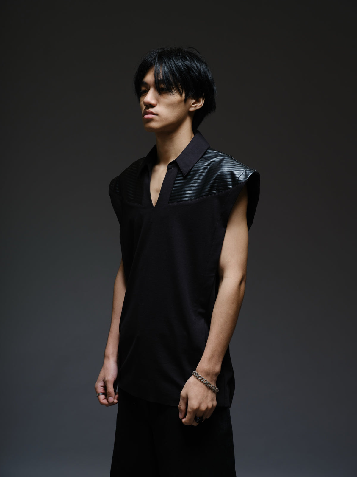 Onyx black sleeveless Roma knit tee with extended shoulders, stitched leather chest panels, a pointed collar and an open V neckline