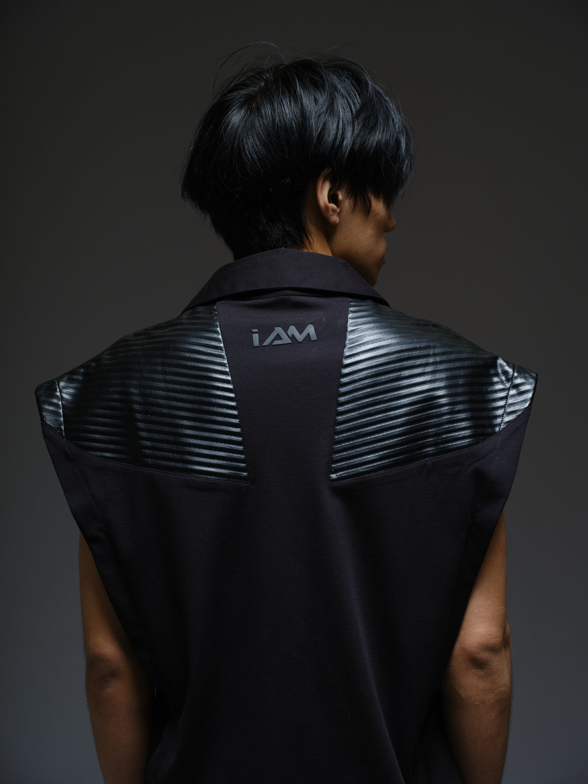 Onyx black sleeveless Roma knit tee with extended shoulders, stitched leather chest panels, a pointed collar and an open V neckline
