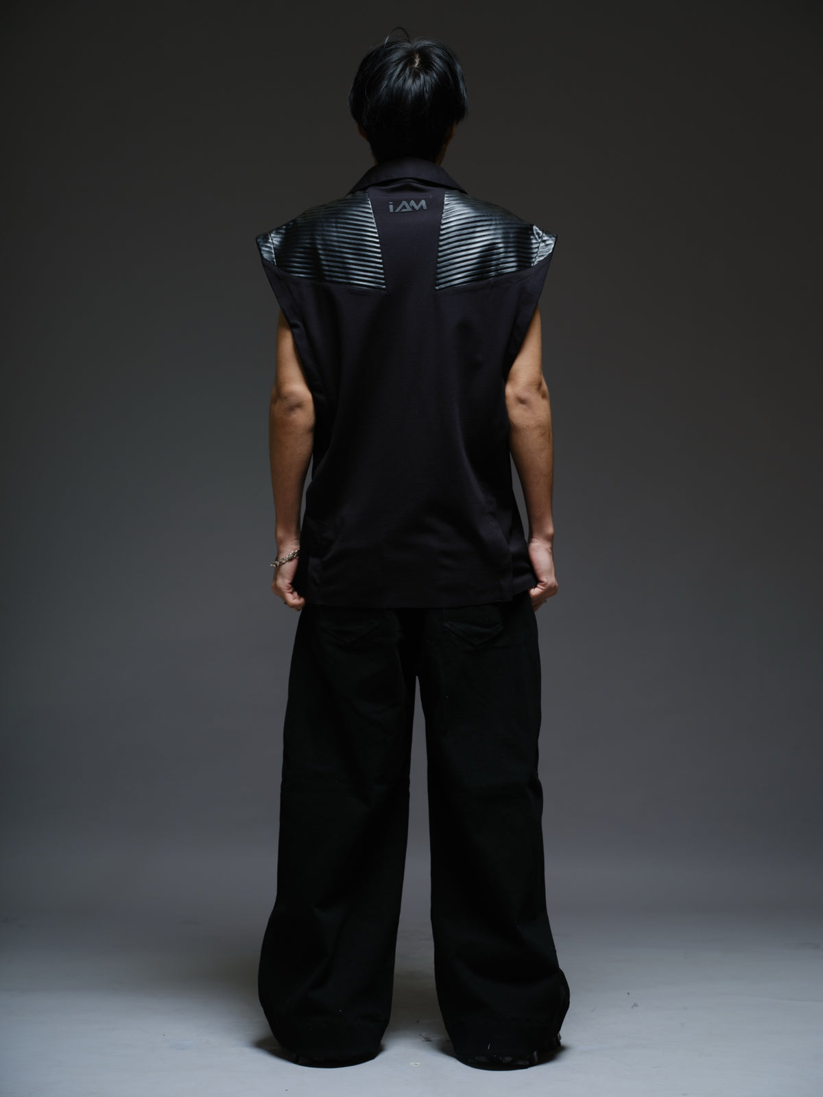 Onyx black sleeveless Roma knit tee with extended shoulders, stitched leather chest panels, a pointed collar and an open V neckline