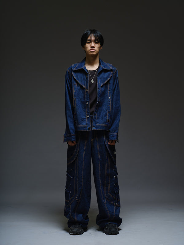 Indigo Set 2.0 blue denim jacket with orange stitching, a broad collar, curved chest panels, metal eyelets and pointed cuffs