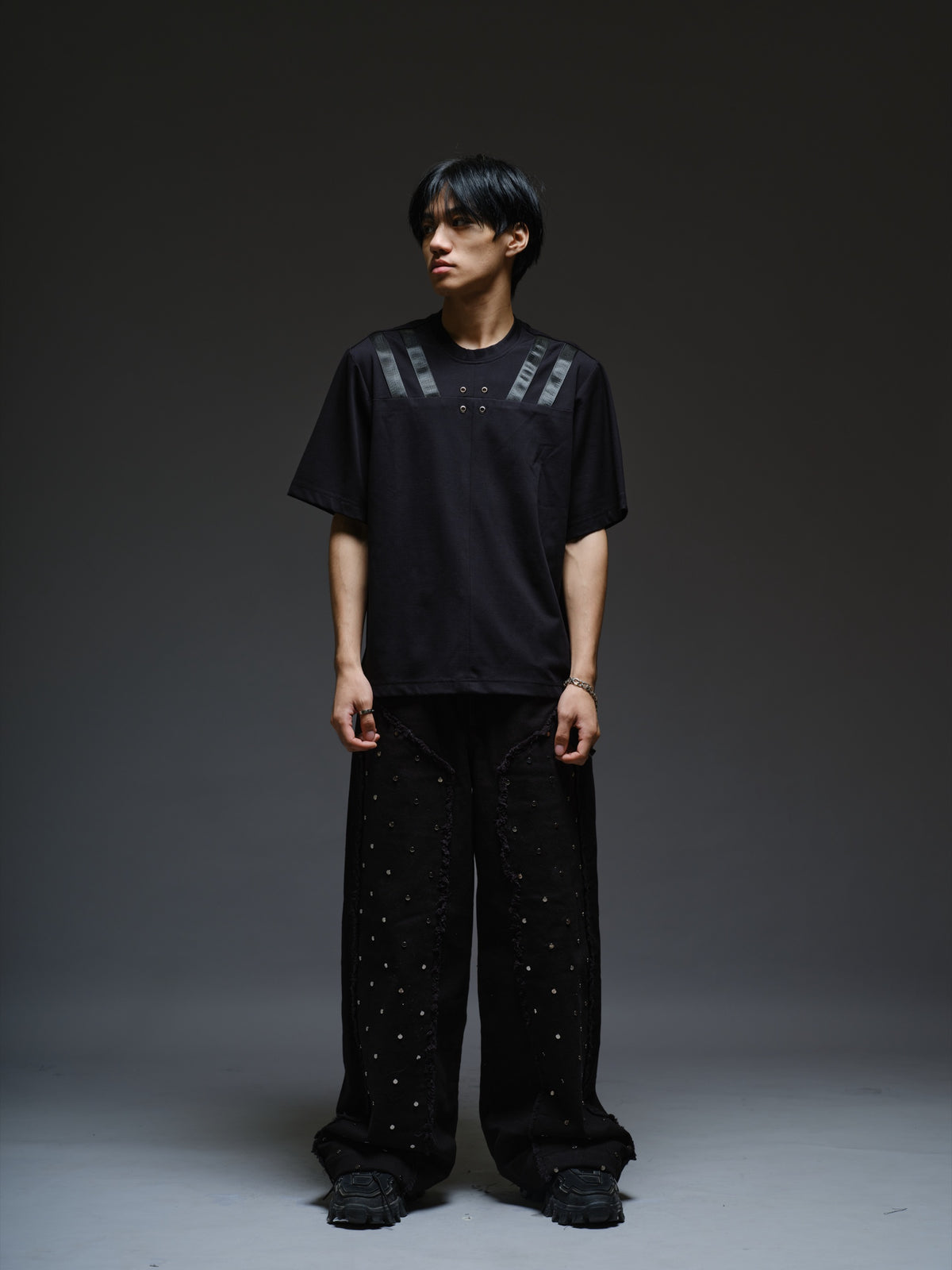Relaxed black Roma knit T-shirt with angled black leather shoulder straps, four centre-chest rivets and short sleeves.