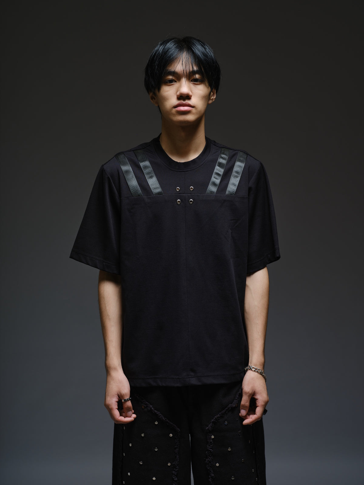 Relaxed black Roma knit T-shirt with angled black leather shoulder straps, four centre-chest rivets and short sleeves.