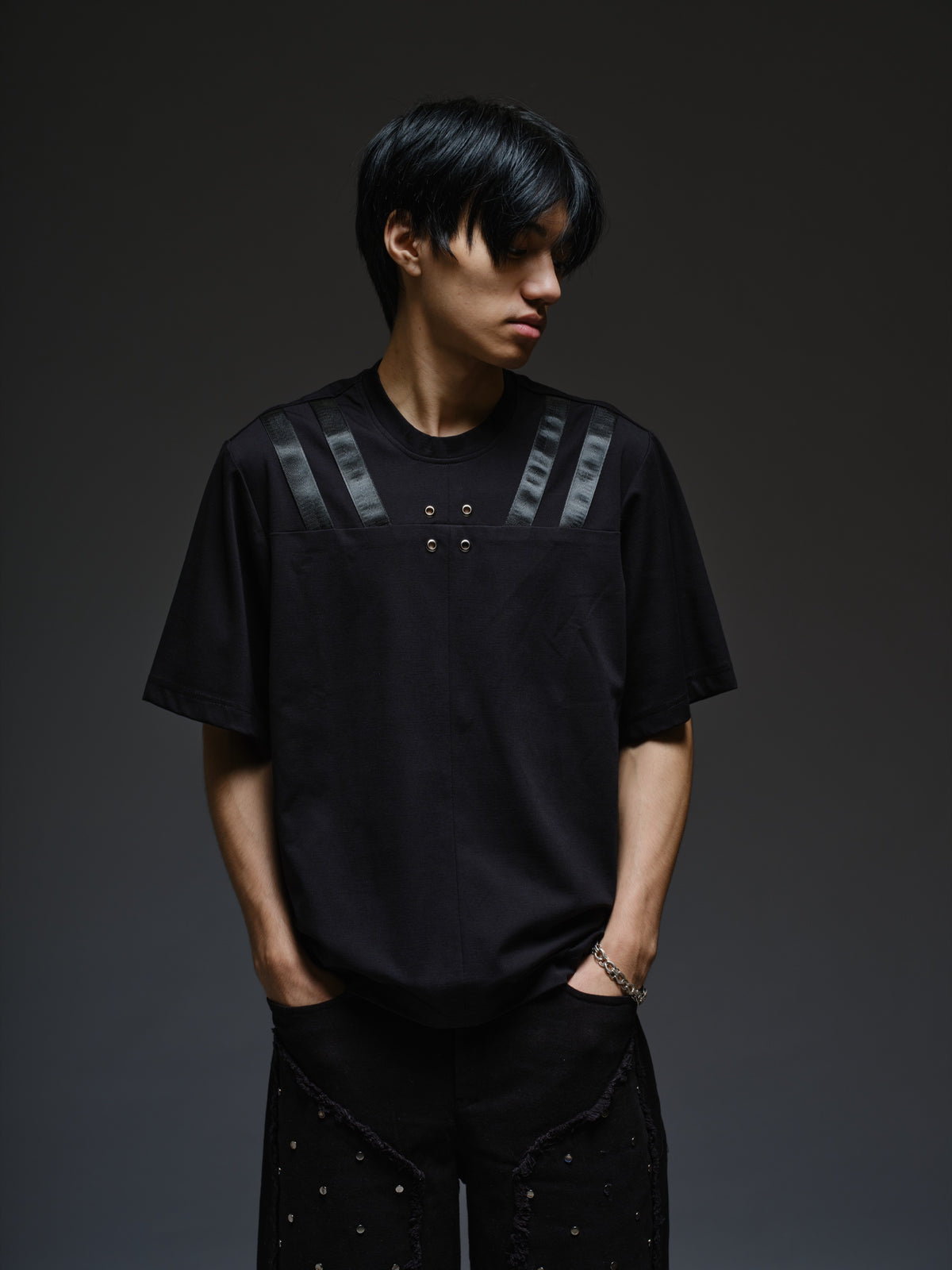 Relaxed black Roma knit T-shirt with angled black leather shoulder straps, four centre-chest rivets and short sleeves.