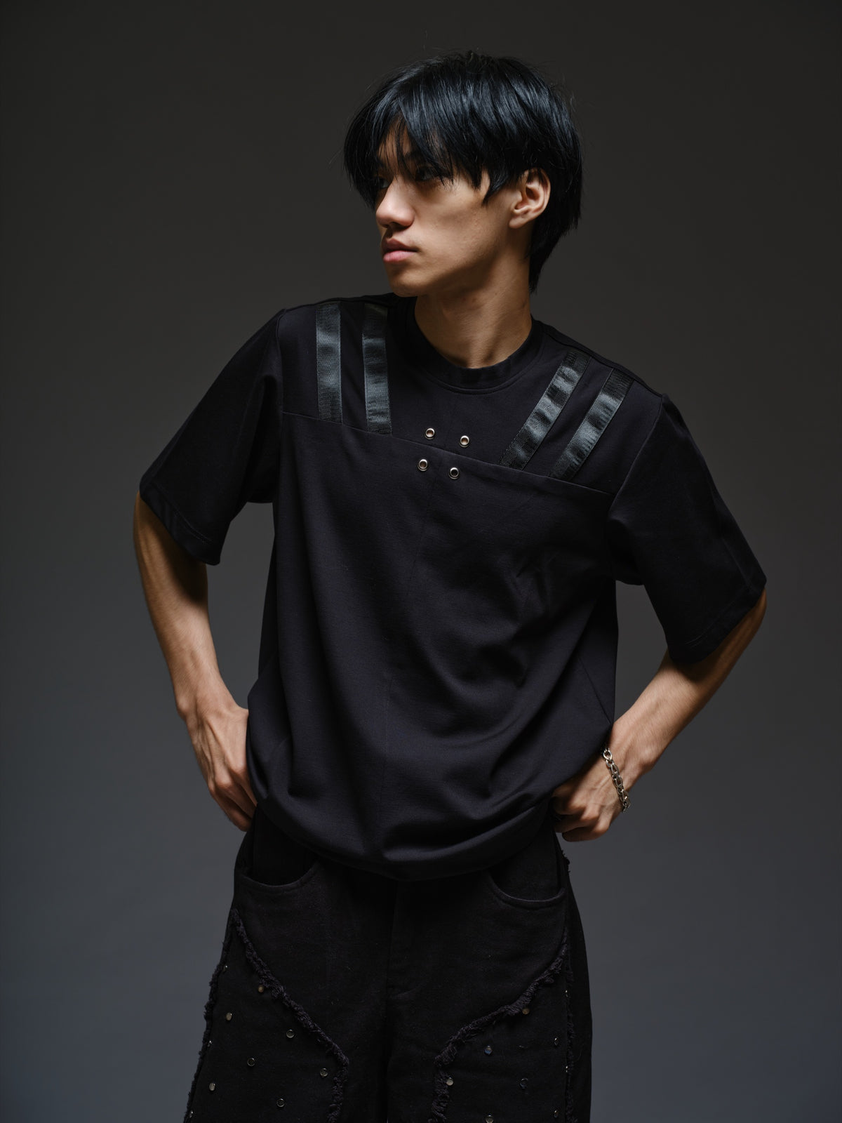 Relaxed black Roma knit T-shirt with angled black leather shoulder straps, four centre-chest rivets and short sleeves.