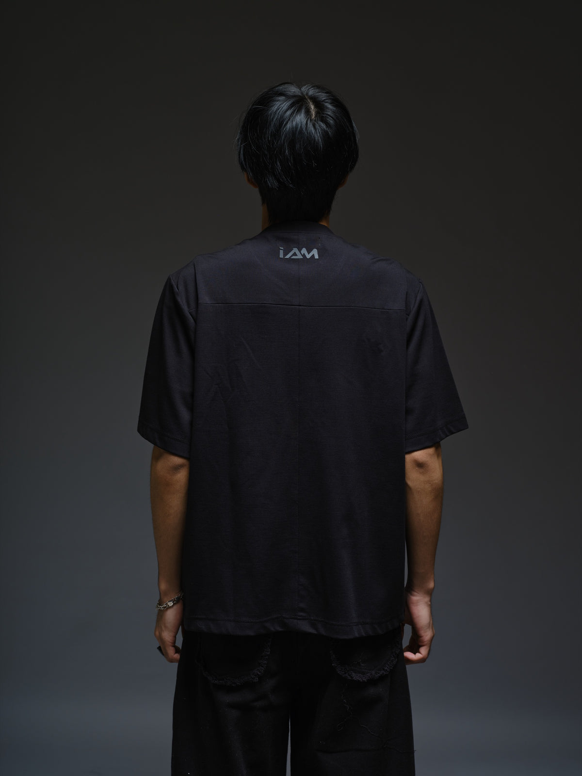 Relaxed black Roma knit T-shirt with angled black leather shoulder straps, four centre-chest rivets and short sleeves.