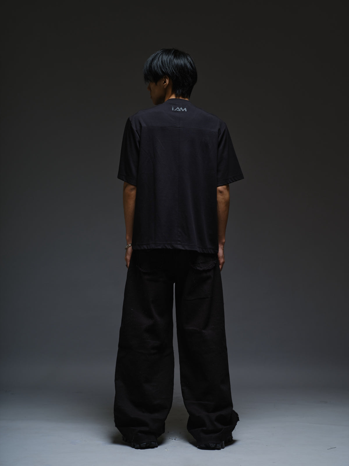 Relaxed black Roma knit T-shirt with angled black leather shoulder straps, four centre-chest rivets and short sleeves.